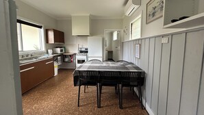 A compact kitchen with a dining area, featuring a stove, microwave, and sink.