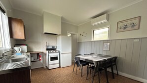 A compact kitchen with a sink, stove, oven, and a dining table with chairs.
