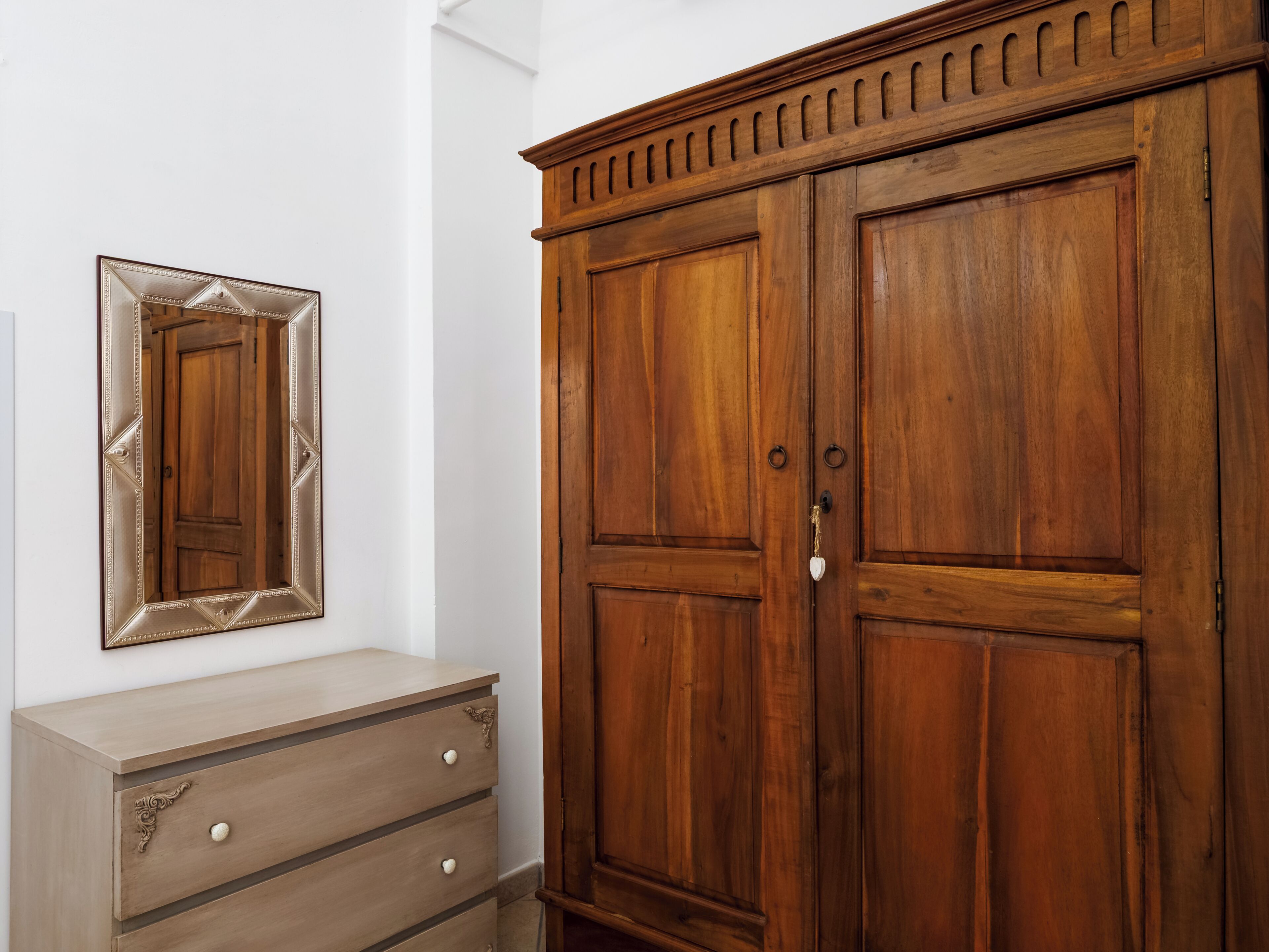 A wooden wardrobe with two doors, a mirror, and a dresser with drawers.