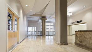 Un'ampia hall con una reception, una segnaletica che indica il terzo piano e una vista esterna attraverso ampie finestre.