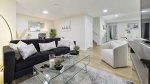 Ein modernes Wohnzimmer mit einem schwarzen Sofa, einem Glastisch und einem weißen Sessel.