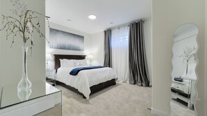Ein modernes Hotelzimmer mit einem großen Bett, einem Nachttisch mit Lampe, einem Glastisch und einer dekorativen Vase.