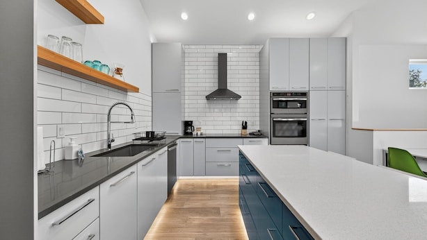Een moderne keuken met witte kasten, een zwart aanrecht en een houten vloer.