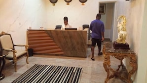 Un espace d’accueil doté d’un comptoir de réception en marbre, d’une statue dorée et d’un tapis à rayures.