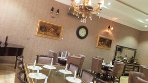 Un coin repas agrémenté d’un lustre, de tableaux encadrés et d’une horloge murale.