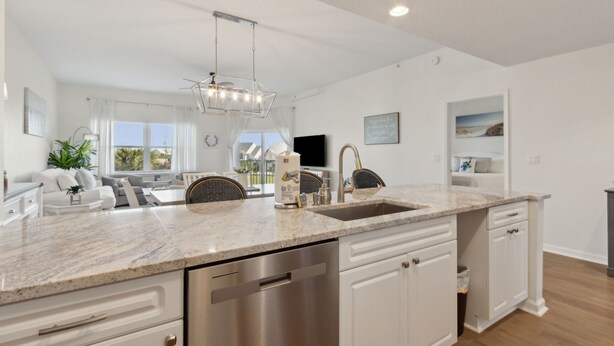A modern kitchen with a marble countertop, stainless steel appliances, and a pendant light. - Ocean Park 118 - Hosted by Moore AI Rentals (Fernandina Beach)