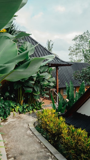 A traditional building with a curved roof, surrounded by lush greenery and a concrete pathway. - Mina Baturiti Hotel & Resto (Baturiti)