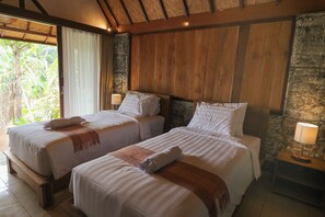 A room with two beds, wooden headboards, and a stone wall. - Mina Baturiti Hotel & Resto (Baturiti)