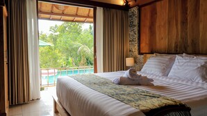 A hotel room with a large bed, a view of greenery outside, and a wooden ceiling. - Mina Baturiti Hotel & Resto (Baturiti)