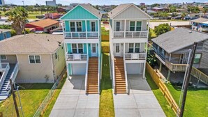 A residential area with two two-story houses featuring front porches and a central staircase. - New! Galveston Retreat -Sleeps 10-EV Charger -Fast WiFi -Near Beach (Galveston)