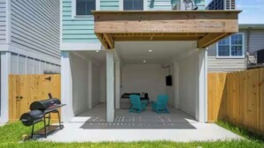 A covered patio with a grill and two chairs. - New! Galveston Retreat -Sleeps 10-EV Charger -Fast WiFi -Near Beach (Galveston)