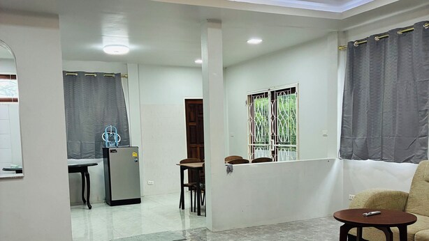 A spacious living area with a marble floor, a sofa, a small table, and a kitchen area in the background. - The Green Horizon Villa Chaweng Hill (Koh Samui)