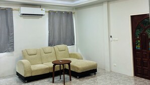 A living room with a beige sofa, a small wooden table, and a ceiling light fixture. - The Green Horizon Villa Chaweng Hill (Koh Samui)