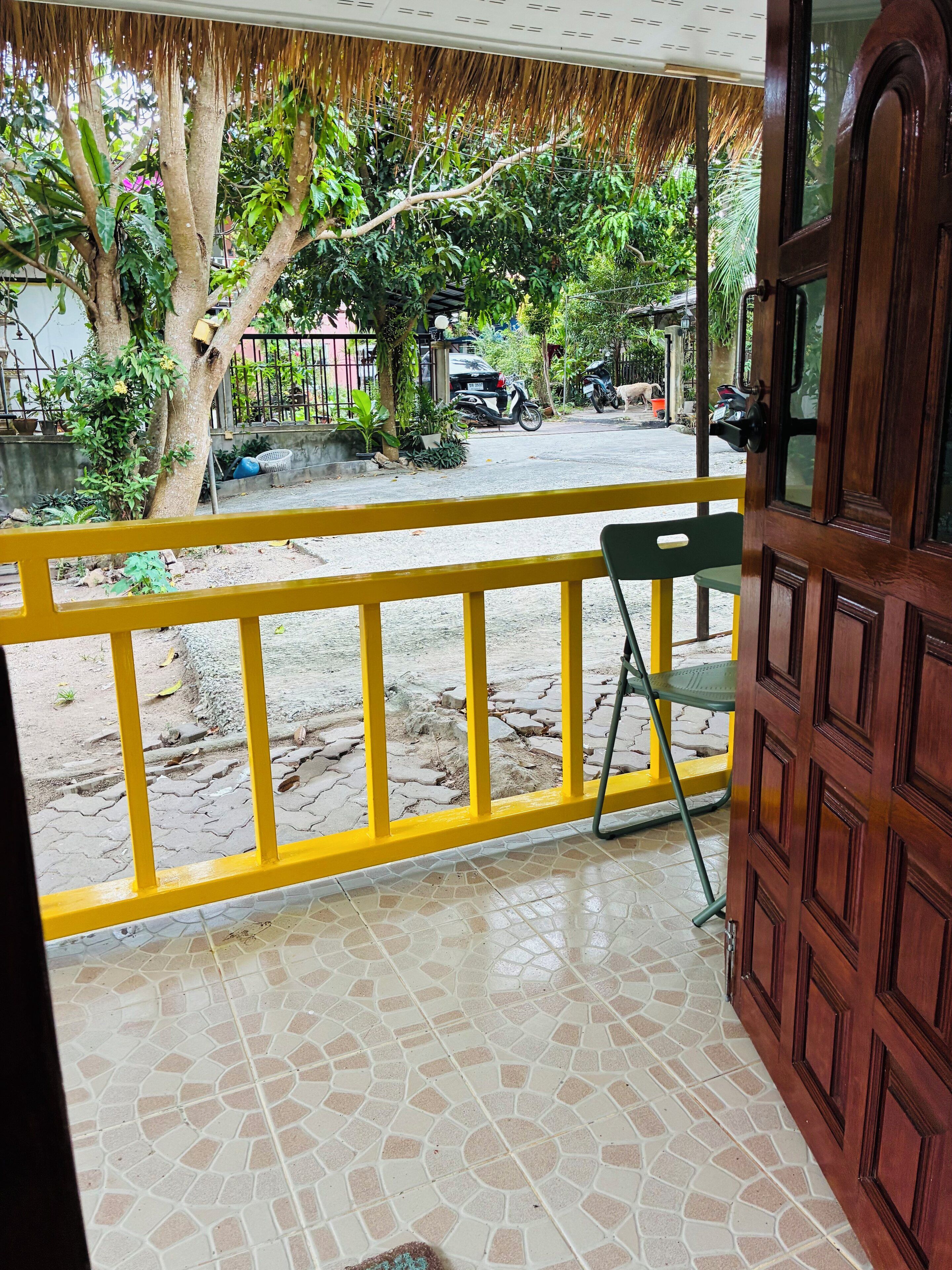 A wooden door with a glass panel, a yellow railing, and a tiled floor.