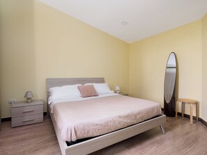 A bedroom with a bed, bedside tables, a mirror, and a small stool.