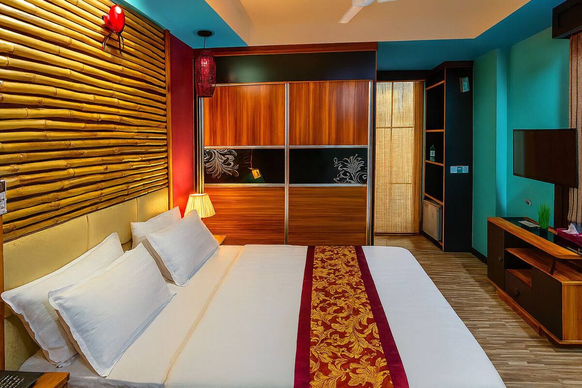 Una camera d'albergo moderna con un letto grande, una testiera in legno, una TV e un armadio.