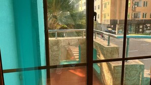 A balcony with a view of a cityscape, including buildings and a palm tree. - Rara HM (Hulhumale)
