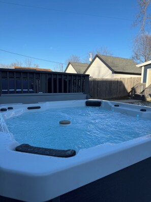 A hot tub with a wooden deck and a house in the background. - Spacious Home for Groups with Hot Tub in Indy (Indianapolis)