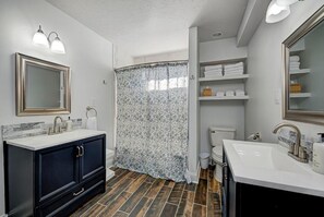 A bathroom with a double sink, a shower curtain, and a toilet. - Spacious Home for Groups with Hot Tub in Indy (Indianapolis)