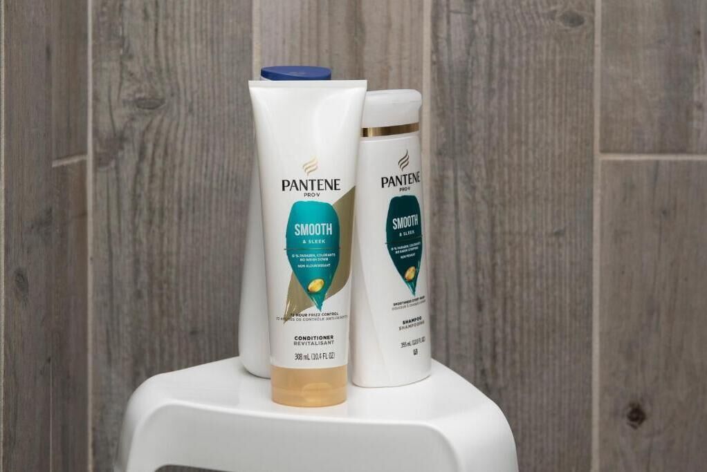 Two Pantene Pro-V Smooth & Sleep conditioner bottles on a white surface against a wooden background.