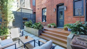 A courtyard with a brick building, outdoor seating, and potted plants. - The Regent on Whitaker | Downtown Savannah Luxury (Savannah)