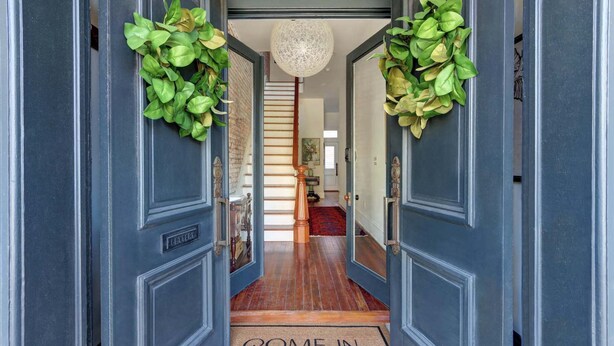 A hallway with dark blue doors, a 'COME IN' mat, and green foliage decorations. - The Regent on Whitaker | Downtown Savannah Luxury (Savannah)