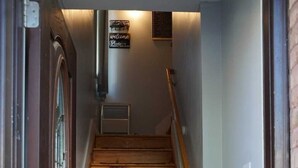 Una escalera de madera con barandilla, un cartel de bienvenida y un tapete al pie.