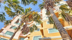 A multi-story hotel with a yellow facade, large windows, and palm trees. - Bhanwar Singh Palace Pattaya (Pattaya)
