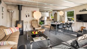 A modern living room with a sofa, a coffee table with fruit, a fireplace, and a dining area with chairs and a TV. - "Vilhelm" - 10km from the sea by Interhome (Oksbøl)