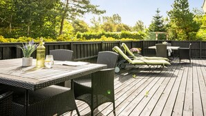A wooden deck with a table and chairs, surrounded by greenery and trees. - "Vilhelm" - 10km from the sea by Interhome (Oksbøl)
