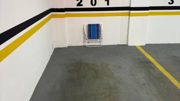 A parking garage with numbered parking spaces, a directional exit sign, and a chair in the center.
