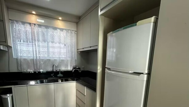 Una cocina moderna con electrodomésticos de acero inoxidable, encimera negra y armarios blancos.