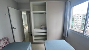 Un dormitorio con dos camas, un armario y vistas a edificios.
