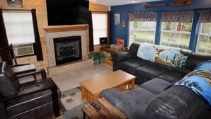 Una sala acogedora con chimenea, sofá de cuero y televisor.