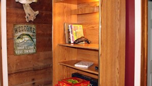 Una estantería de madera con libros y objetos decorativos, un cartel de bienvenida y un adorno con forma de pez en la pared.