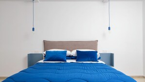 Et moderne soveværelse med en stor seng, blåt sengetøj og to sengeborde med lamper.