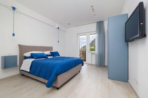 Ein Schlafzimmer mit Bett, einem an der Wand montierten Fernseher und einem Fenster mit Blick ins Freie.