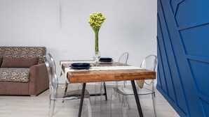 Et moderne spiseområde med et træbord, gennemsigtige stole, en vase med blomster og en blå lysekrone.
