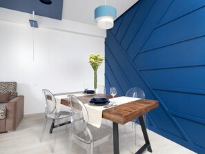 Ein moderner Essbereich mit Holztisch, transparenten Stühlen und einer blauen Akzentwand.