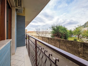Ein Balkon mit Blick auf eine Stadtansicht, eine blaue Tür und ein Metallgeländer.