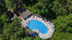 An aerial view of a swimming pool surrounded by lush greenery, with lounge chairs and a covered patio area. - Smoky Mountain Condo with Scenic Views, Pool, & Fireplace – 10 Min to Downtown (Gatlinburg)