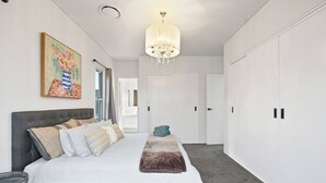 Une chambre à coucher avec un grand lit, un lustre, une armoire et un tableau au mur.