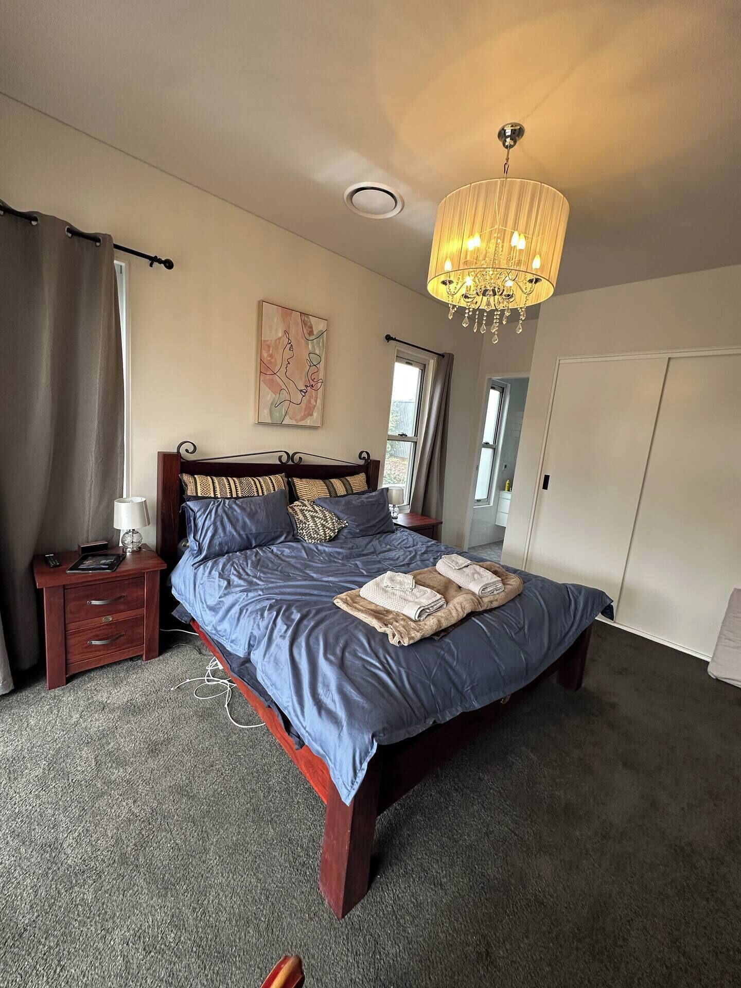 Une chambre à coucher avec un grand lit, une table de chevet, une lampe, un lustre et une carte accrochée au mur.