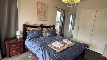 Une chambre à coucher avec un grand lit, une table de chevet, une lampe, un lustre et une carte accrochée au mur.