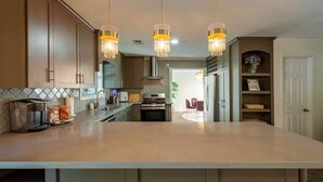 A modern kitchen with a large island, stainless steel appliances, and pendant lighting. - Peacock Paradise - Pool / Game (Houston)