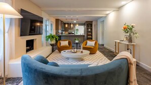 A modern living room with a sofa, two armchairs, a coffee table, and a TV mounted on the wall. - Peacock Paradise - Pool / Game (Houston)