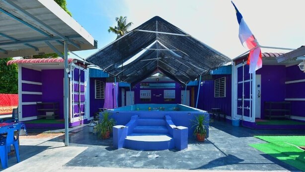 Zona de piscina con piscina azul, área de estar techada y una bandera.
