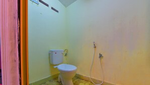 Un baño pequeño con inodoro, ducha y suelo de baldosas.