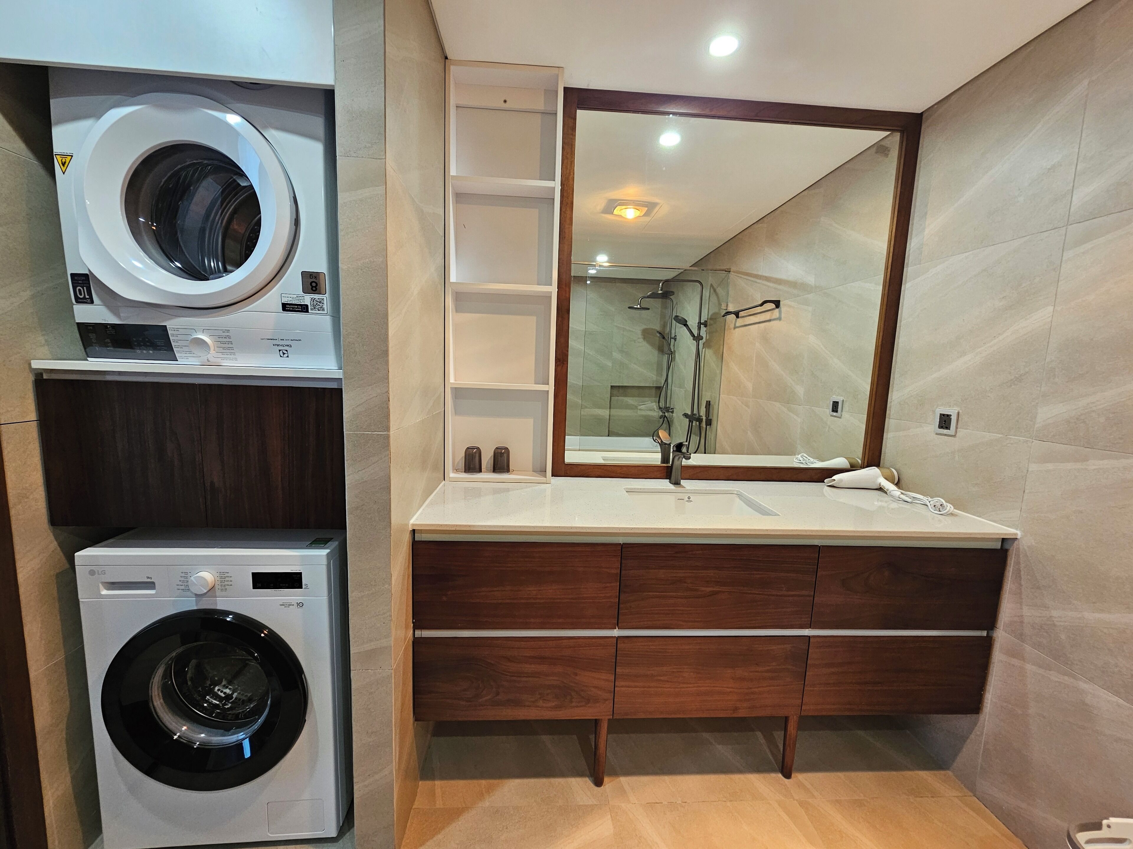 Un baño moderno con lavadora integrada, un espejo grande y un mueble de tocador con lavabo.