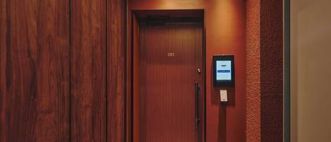 A wooden door with the number 201, a keypad, and a security camera above it.